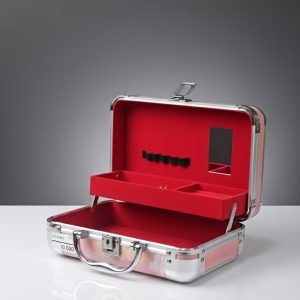 Estuche de maquillaje/ joyero de aluminio con un interior rojo forrado de terciopelo o tela sintética.