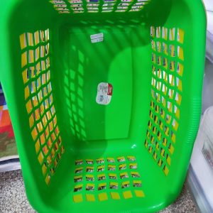 Cesta de la ropa de plástico de color verde, comúnmente utilizada para almacenar y transportar ropa sucia o limpia