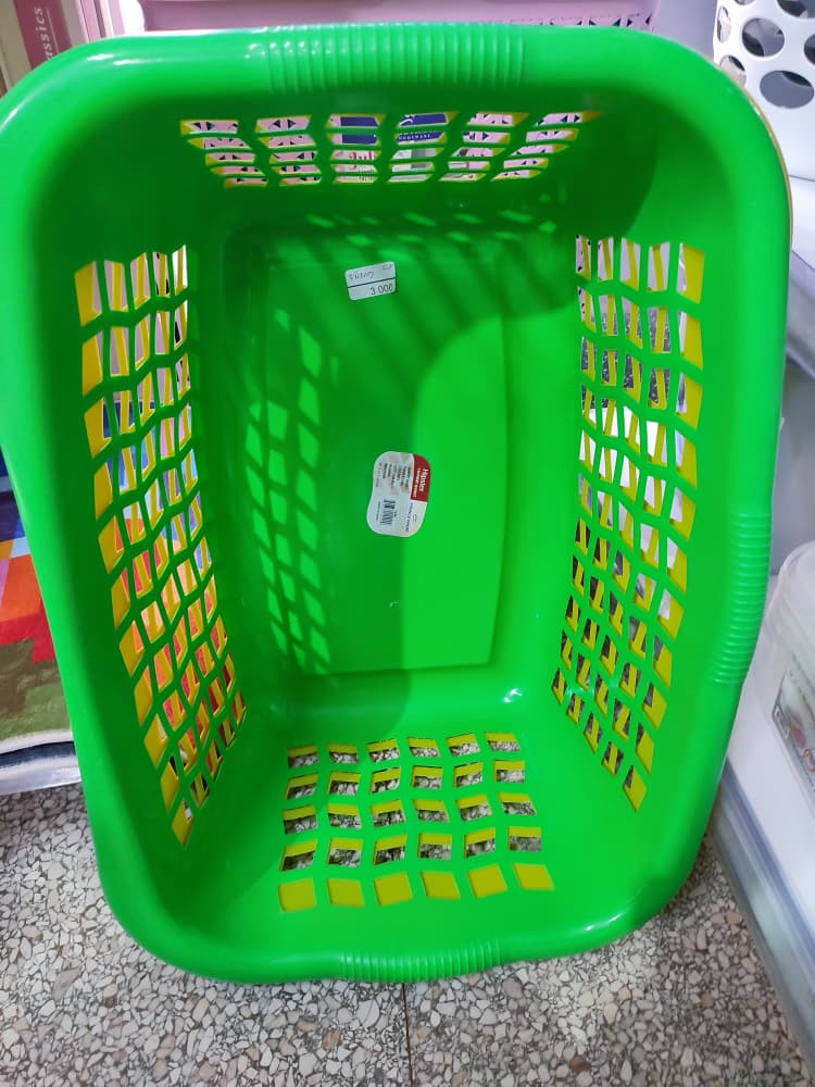 Cesta de la ropa de plástico de color verde, comúnmente utilizada para almacenar y transportar ropa sucia o limpia