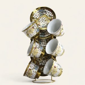 Juego de tazas y platillos de porcelana con un diseño ornamentado en blanco y dorado, junto con una tetera a juego